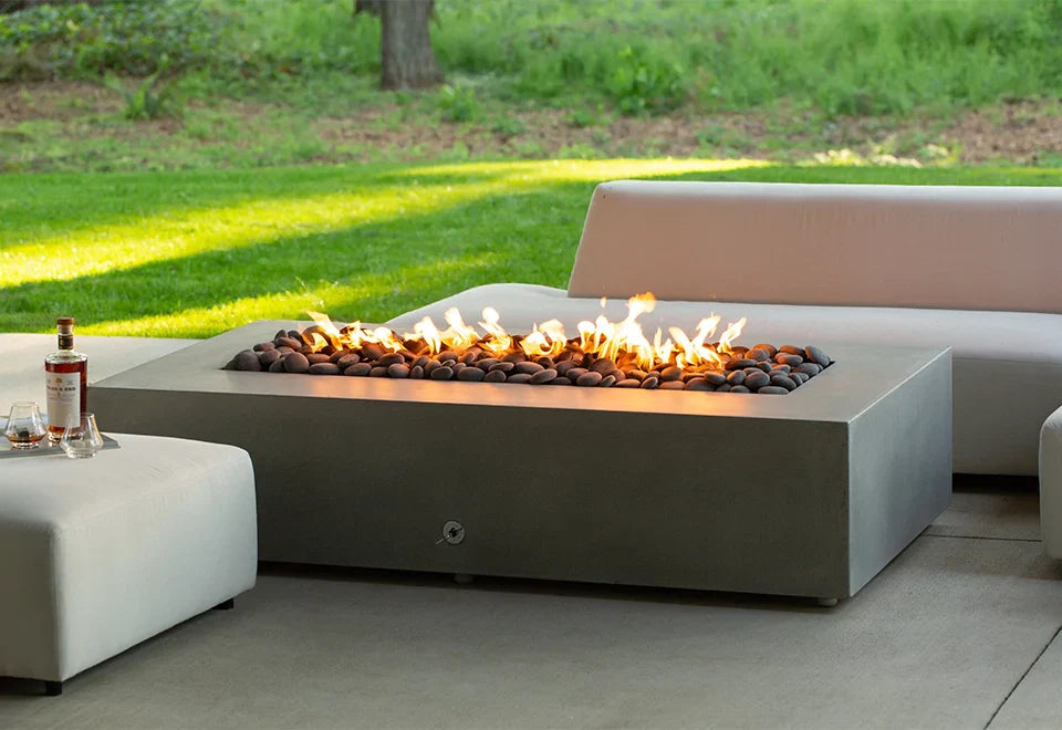 outdoor propane fire pit next to couch with liquor bottle